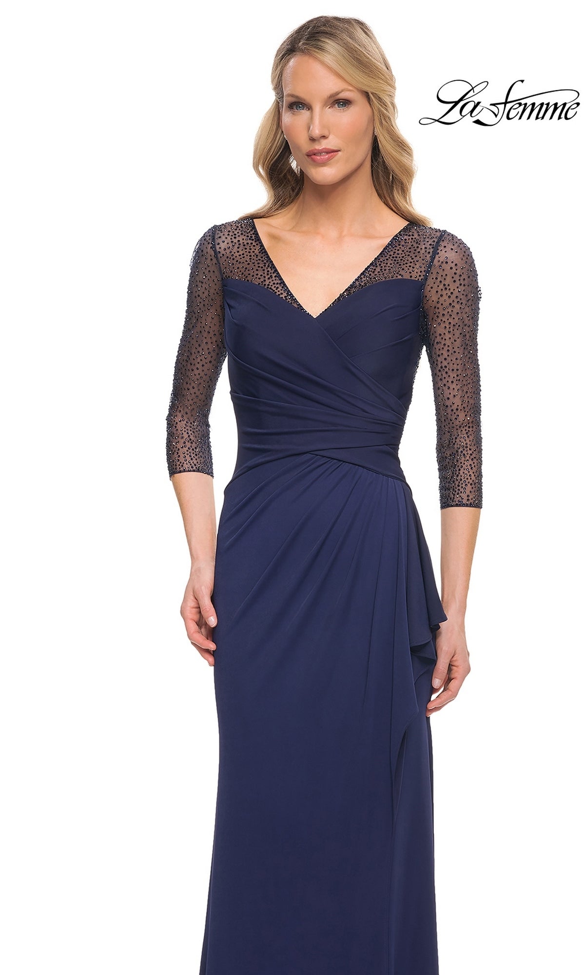Woman wearing Long Formal Dress: La Femme 30028—navy blue jersey, V-neck, ruched waist, beaded applique sleeves. “La Femme” logo in top right corner.